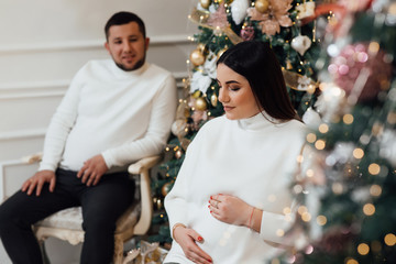A pregnant woman and her husband in the studio. Christmas and New Year