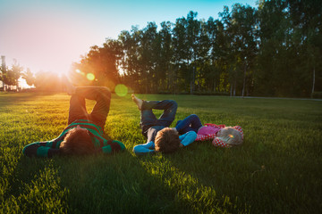 father with son and daughter relax on green grass at sunset