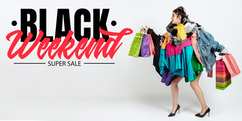 Black weekend, finance concept. Woman addicted of sales and clothes. Female model wearing too much colorful clothes. Fashion, style, black friday, sale, purchases, money, online buying. Flyer for ad.
