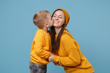 Fototapeta premium Woman in yellow clothes have fun posing with cute child baby boy 4-5 years old. Mommy little kid son isolated on blue background studio portrait. Mother's Day love family parenthood childhood concept.