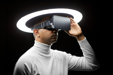 future technology, augmented reality and people concept - man in virtual reality headset or vr glasses under white illumination over black background