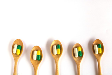 Colorful of capsule pills in wooden spoon  on white background.