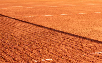 Clay tennis court with a net shadow on it. Outdoor red tennis court. Background, texture, space for...