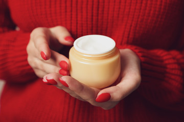 Woman holding jar of moisturizing cream, closeup. Winter cosmetic. Space for text