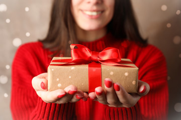 Young woman holding gift box, closeup. Space for text