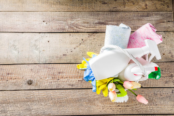 Spring home cleaning and housekeeping concept, Basket with cleaning items, utensils, supplies. Copy space over wooden background with spring blossom flowers