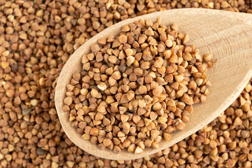 glass jar with buckwheat and a wooden spoon on white isolate background