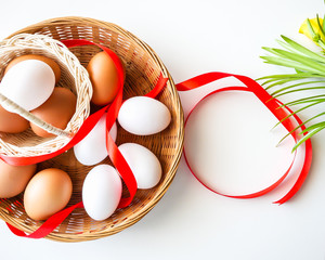 Healthy food concept, Isolated gift set of fresh duck and chicken eggs in basket with red ribbon decorated on white table background-top view