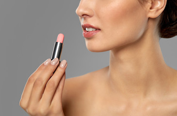 Naklejka premium beauty, makeup and cosmetics concept - happy smiling young woman with pink lipstick over white background