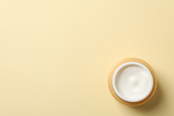 Jar of winter cream for skin on yellow background, space for text. Top view