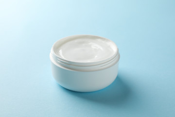 Jar of winter cream for skin on blue background, space for text. Closeup