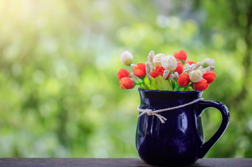 Vase with artificial flowers on a natural background.