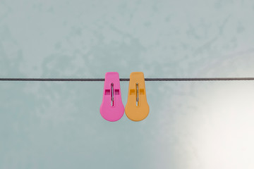 plastic​ clothespins pink​ and yellow color​​ ​ on​ wall background