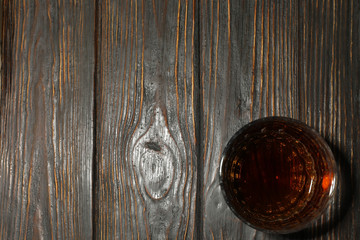 Glass of whiskey on wooden background, space for text