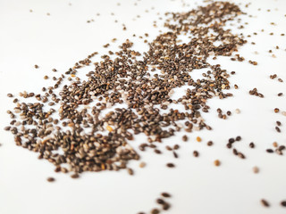Fototapeta premium Zbliżenie superfood nasion chia surowych i organicznych na białym tle, z nasionami losowo umieszczonymi w przestrzeni