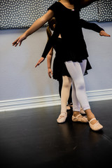 Black girl in front of line practices footing in ballet class