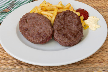 Un plato con dos hamburguesas y patatas fritas