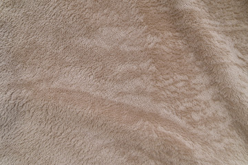 Fluffy beige plaid background, close up. Delicate baby pastel fabric with waves and pleats. Wrinkled beige warm blanket background