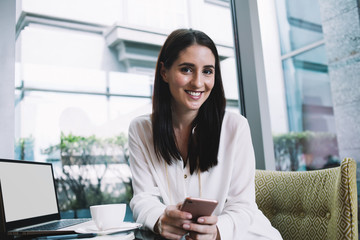 Smiling woman working in cafe with devices