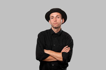 Stylish handsome man a black shirt and pork pie hat over grey background