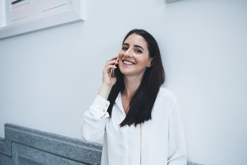 Happy lady speaking on phone leaning on wall