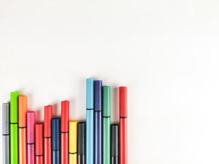 Colorful pens lined randomly on one corner of the image making an interesting decoration for white background leaving empty space to fill