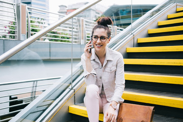 Stylish woman talking on phone on building steps