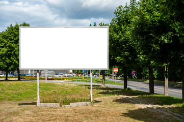 Blank white billboard for advertisement in the city. Sumeer day, blue sky with some white clouds.