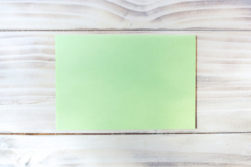 Empty piece of green paper on wooden background. Texture, empty writing space