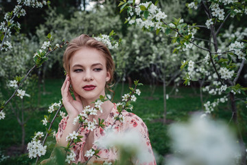 Young beautiful woman in the cherry-blossoming garden.