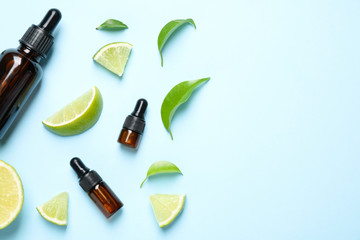 Flat lay composition with lime essential oil on light blue background. Space for text
