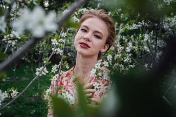 Young beautiful woman in the cherry-blossoming garden.