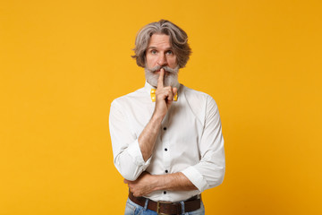 Elderly gray-haired mustache bearded man in white shirt bow tie posing isolated on yellow...