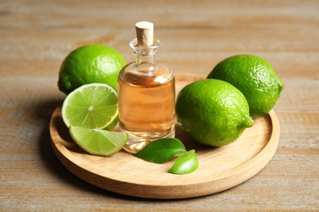 Lime essential oil and citrus fruits on wooden table
