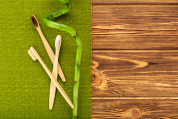 Bamboo toothbrushes, bamboo branch on wooden background. Flat lay copy space. Natural bath products. Biodegradable natural bamboo toothbrush. Eco friendly, Zero waste, Dental care Plastic free concept