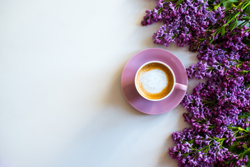Fototapeta na wymiar Floral composition made of beautiful purple lilac, syringa flowers on white background with cup of coffee. Feminine office desk, styled stock image, flat lay, top view with empty space.
