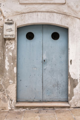 Gray-blue door in a stone wall. Round holes. Closed, lock. Mailbox.
