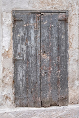 Gray wooden door in a stone wall. Closed, lock. Old rotten boards.