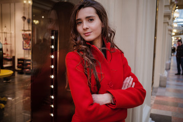 Young beautiful woman in stylish in a long burgundy coat, indoor shop