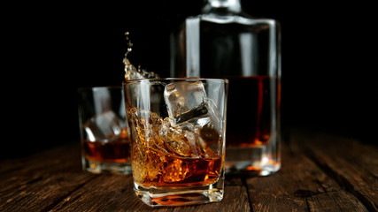 Splashing whiskey from glass with ice cubes inside
