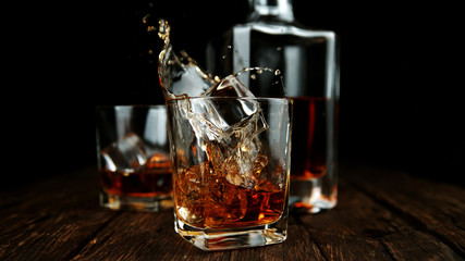 Splashing whiskey from glass with ice cubes inside