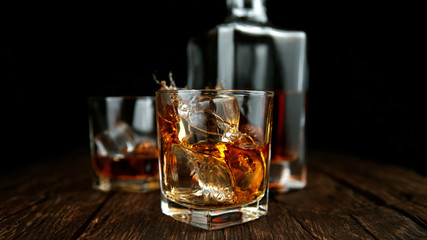 Splashing whiskey from glass with ice cubes inside