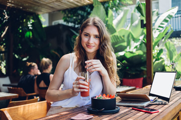 Confident beautiful young woman drinking juice in lounge