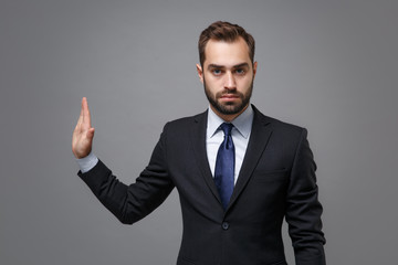 Serious young bearded business man in classic suit shirt tie posing isolated on grey background. Achievement career wealth business concept. Mock up copy space. Showing stop gesture aside with palm.