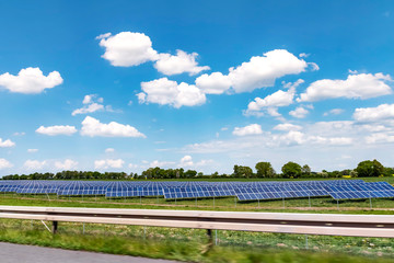 Solar system for sustainable energy generation on a meadow near a freeway in Germany under a sunny sky.