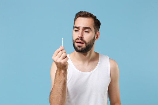 Bearded Man 20s Years Old In White Shirt Hold Cotton Swab Stick For Ear Cleaning Isolated On Blue Pastel Background Studio Portrait. Skin Care Healthcare Cosmetic Procedures Concept Mock Up Copy Space