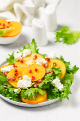 Persimmon pomegranate rucola feta cheese salad. Selective focus, copy space.