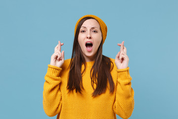 Young brunette woman girl in sweater hat posing isolated on blue background studio portrait. People...