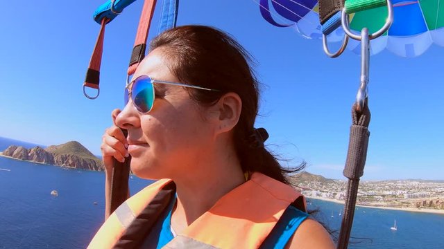 Beautiful girl parasails high above ocean in Cabo San Lucas, Mexico.