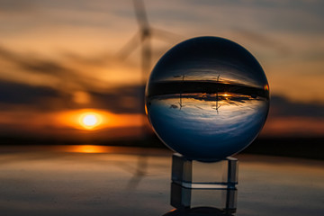 Fototapeta na wymiar Crystal ball sunset shot with reflections on a car roof and power plant silhouette near Kugl, Bavaria, Germany